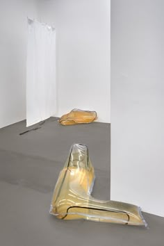 an empty room with plastic coverings on the floor and two sculptures in the background