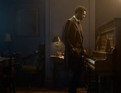 a man standing next to a piano in a dark room