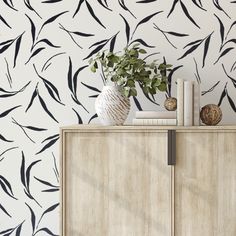 a white cabinet sitting next to a wall with black leaves on it