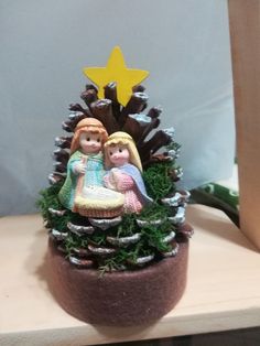 there is a small potted plant with two dolls on it and a star in the background