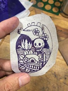 a person holding up a piece of paper with an image of a skull on it