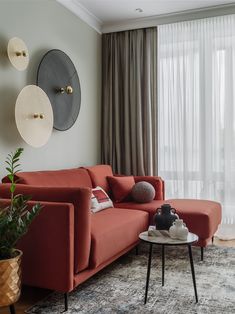 a living room with red couches and two circular mirrors on the wall above them