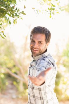 a man pointing at something while standing under a tree in the sun stock photo - 789