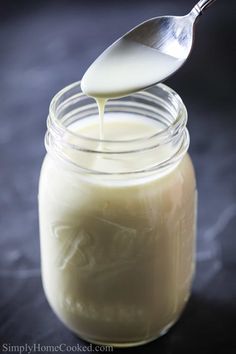 a spoon is pouring milk into a jar