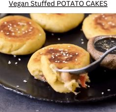 some food on a black plate with a spoon in it and the words vegan stuffed potato cakes