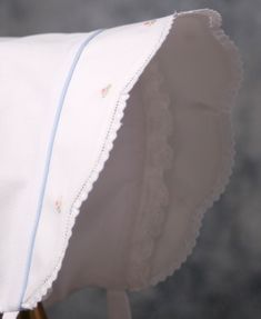 a close up of a white pillow with scalloped edges and blue piping