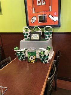 the table is set up with green and white decorations on it, along with two framed pictures