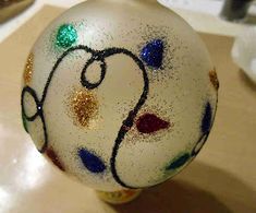 a glass ornament that has been decorated with colored paint and glitters on it