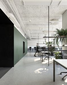 an empty office with tables and plants in the center, along with other desks