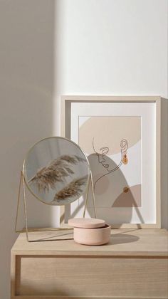 a mirror sitting on top of a wooden table next to a vase with a plant in it