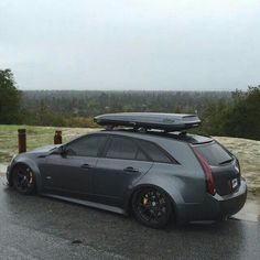 a car with a surfboard on the roof is parked in front of a hill