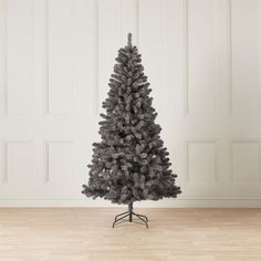 a black christmas tree stands in front of a white wall