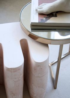 a table with three white stools and a magazine on it's side stand