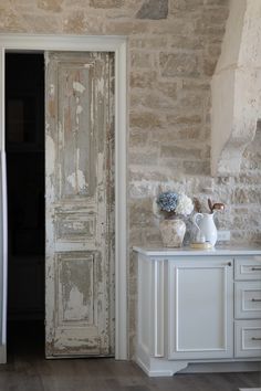 an old door is opened to reveal a room with stone walls and white furniture,