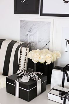 a black and white room with roses in a vase, gift boxes and pictures on the wall