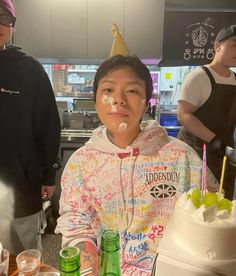 a young boy is sitting in front of a cake with white frosting on it