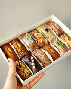 a hand is holding a box of assorted pastries