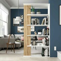 a living room with blue walls and white shelving unit in the middle, along with bookshelves