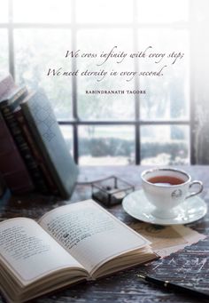 an open book sitting on top of a table next to a cup of coffee