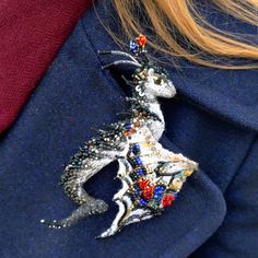 a close up of a person wearing a blue jacket with a silver and red brooch