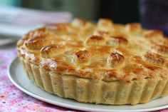 a close up of a pie on a plate with a pink table cloth behind it