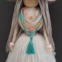 a doll with braids and beads is wearing a white dress, hat and necklace