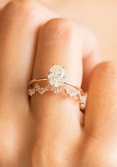 a woman's hand with a diamond ring on top of her finger and an engagement band