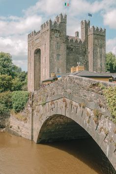 an old stone bridge over a river in front of a castle