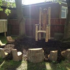 a wooden chair sitting on top of a pile of logs in a yard next to trees