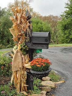 a mailbox is decorated with corn stalks and burlocks for the fall season