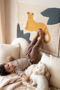 a little boy laying in bed next to a stuffed animal