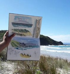 a person holding up an art piece on the beach