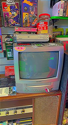 an old tv sitting on top of a wooden shelf in a store filled with books