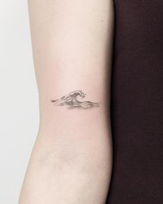 a woman's arm with a small wave tattoo on the back of her left arm