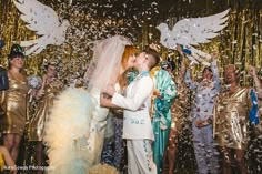 a bride and groom kissing in front of confetti