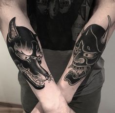 two people with tattoos on their arms holding each other's hands and wearing masks