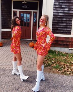 two women in short dresses and white boots posing for the camera