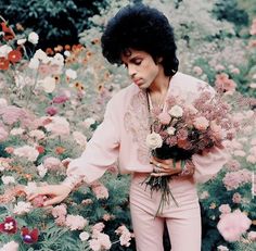 a man holding flowers in his hand and looking at the ground