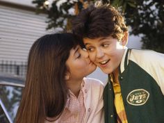 two young people kissing each other in front of a car