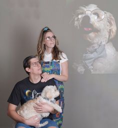 a man and woman holding a dog in front of a wall with an image of a dog on it