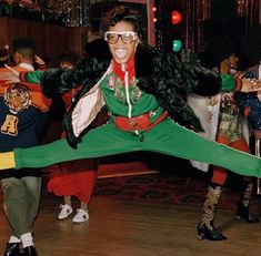 a woman in green and red is dancing on the dance floor with her legs spread out