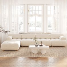 a living room with white furniture and large windows