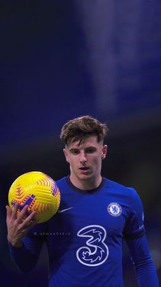 a young man holding a yellow and blue ball