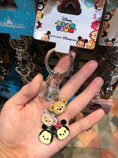 someone is holding some disney key chains in their hand