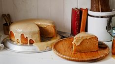 a bundt cake with icing on a wooden plate next to some books and utensils