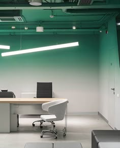 an empty office with green walls and white desks in the foreground, two black chairs on either side