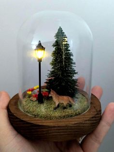 a hand holding a snow globe with a dog in it and a street light on the other side