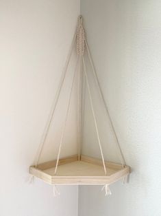 a corner shelf hanging from the wall with rope on it's sides and an empty bowl below