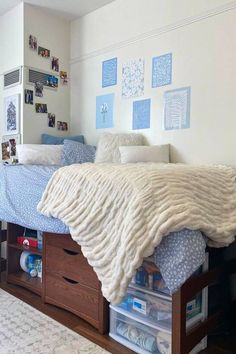 a bed with drawers underneath it and pictures on the wall behind it in a bedroom