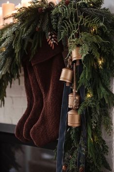 christmas stockings hanging from a mantle with candles and evergreen garland on it's side